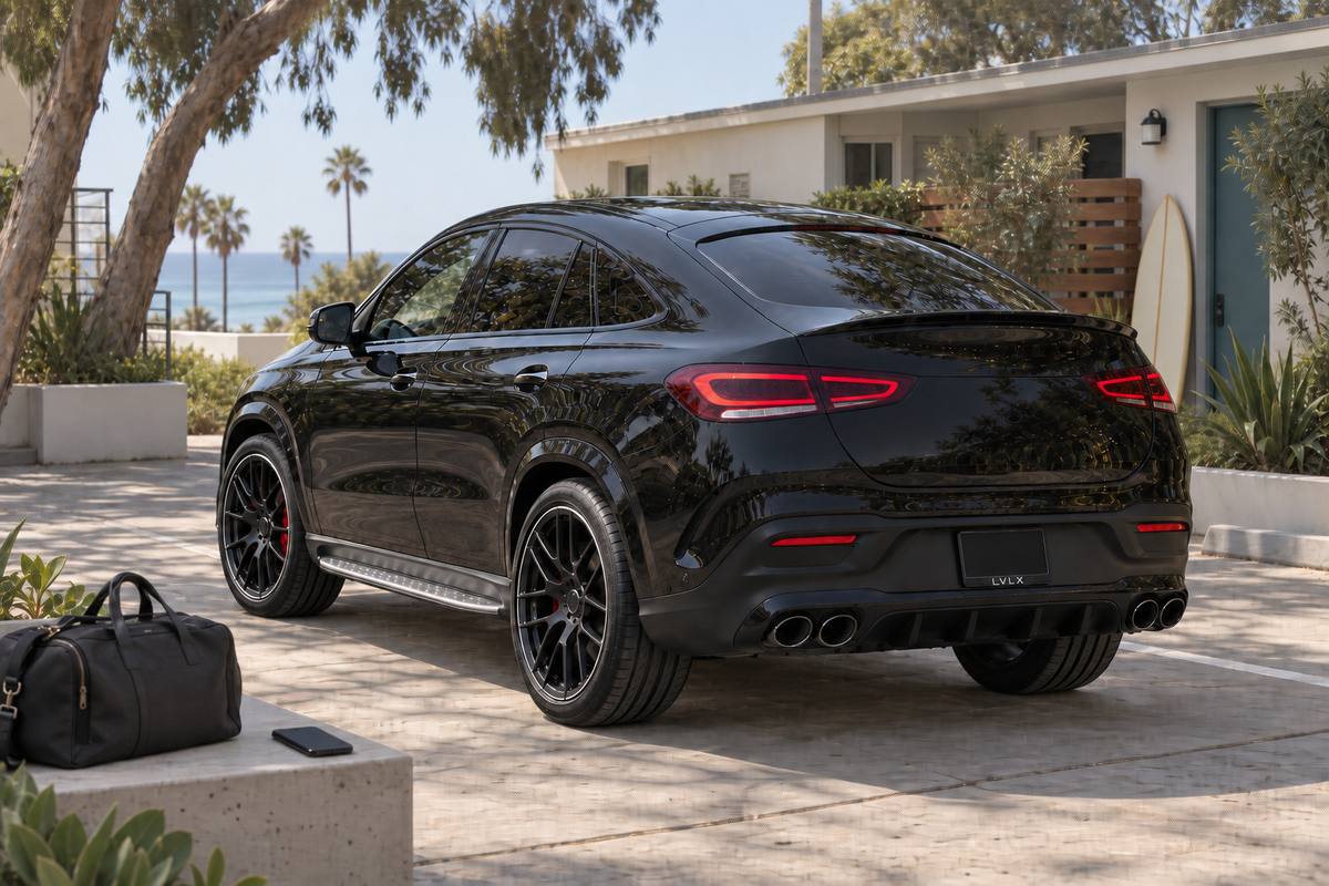Black coupe-style SUV with a bag and phone beside a coastal home.